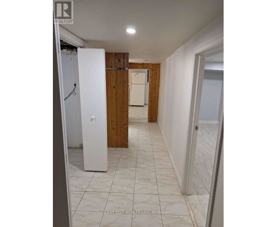 A white refrigerator stands in a kitchen with wooden walls and tile flooring.