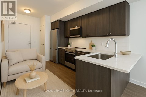 A modern kitchen with a sink, refrigerator, and cabinets.