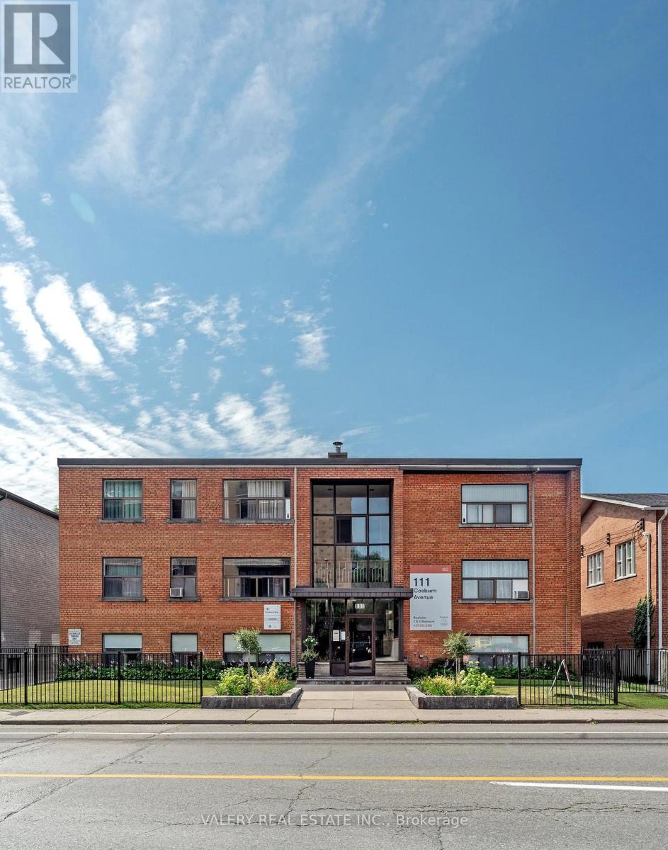 A red brick building with a black fence in front.