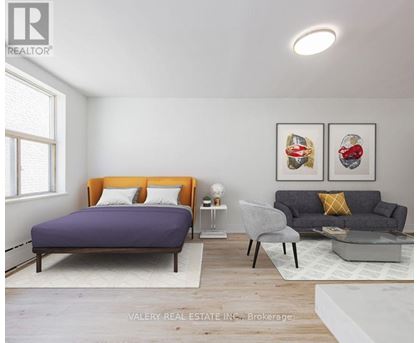 A bedroom with a purple bed and a grey couch.