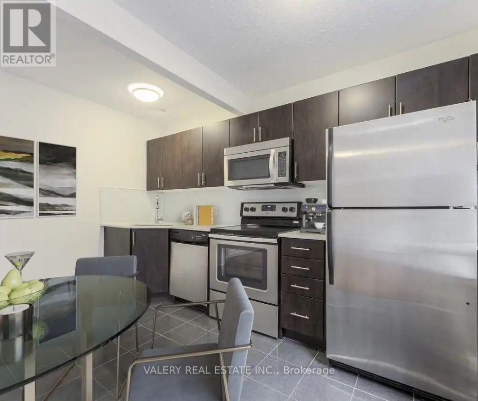 A kitchen with a refrigerator, microwave, oven, and dining table.