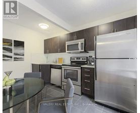 A kitchen with a refrigerator, microwave, oven, and dining table.