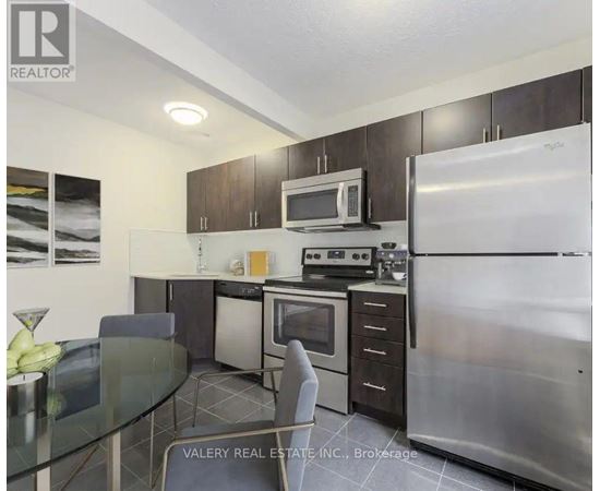 A kitchen with a refrigerator, microwave, oven, and dining table.