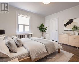 A bedroom with a bed, nightstand, and a plant.