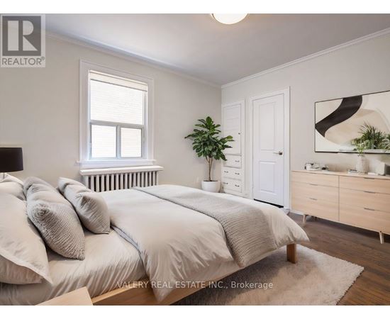 A bedroom with a bed, nightstand, and a plant.
