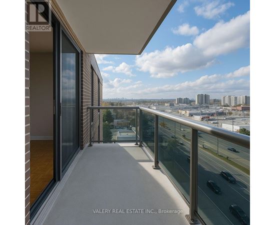 A balcony with a glass railing overlooking a cityscape.