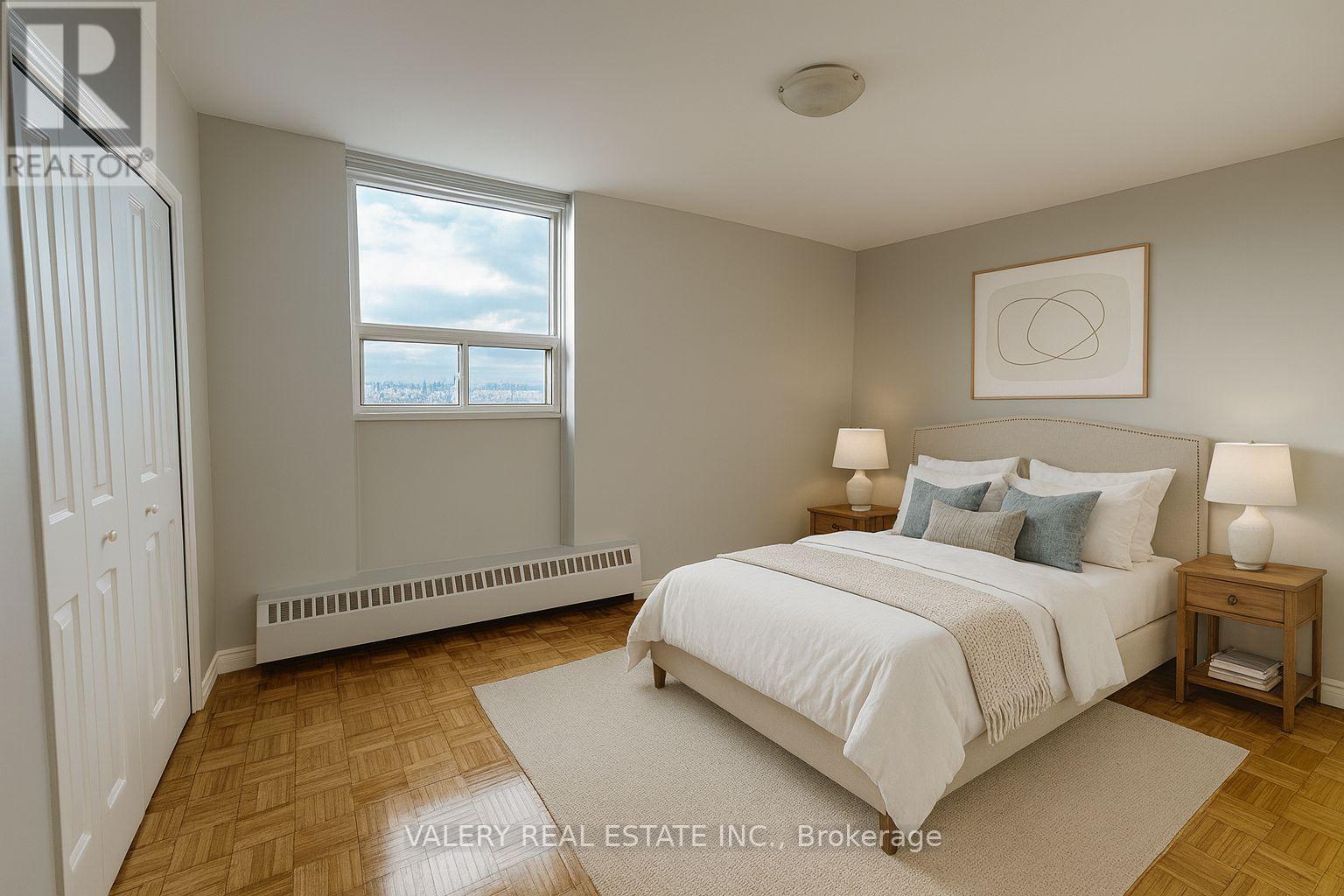 A bedroom with a large bed, a window with a view, and a wooden floor.