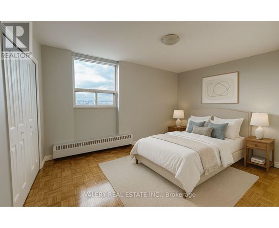 A bedroom with a large bed, a window with a view, and a wooden floor.
