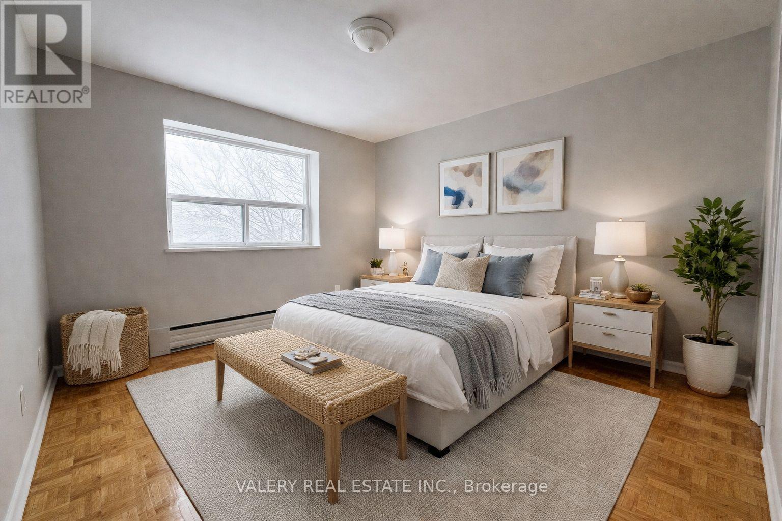 A bedroom with a bed, nightstands, and a plant.