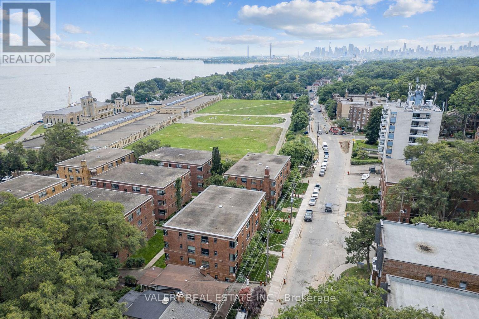 A bird's eye view of a residential area with apartment buildings, a parking lot, and a body of water in the background.