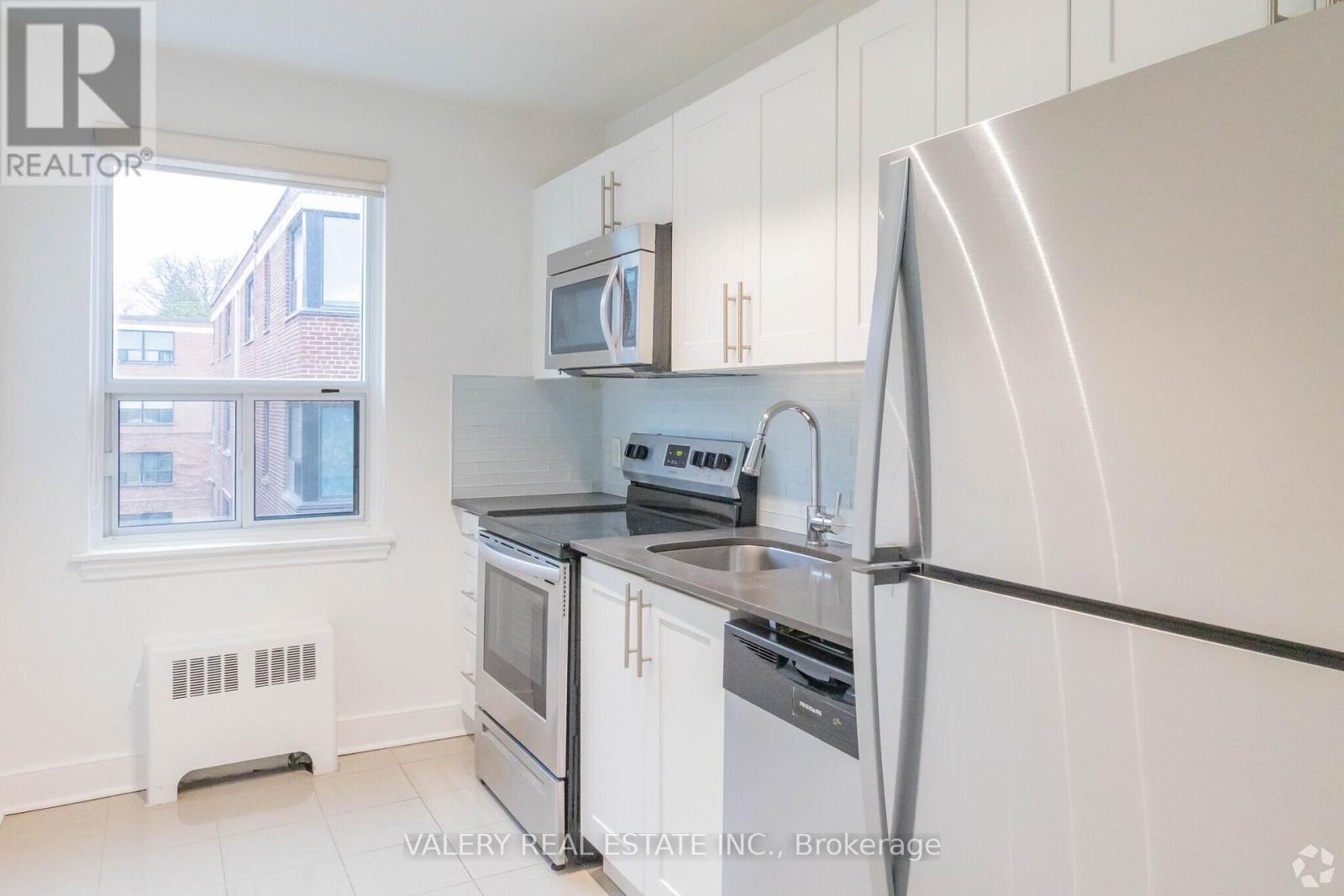 A kitchen with white cabinets and a stainless steel refrigerator.
