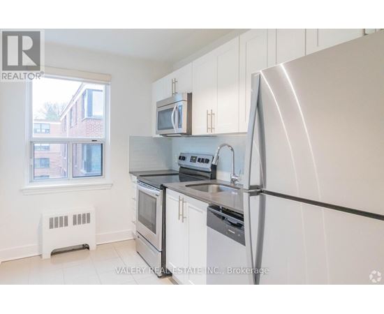 A kitchen with white cabinets and a stainless steel refrigerator.