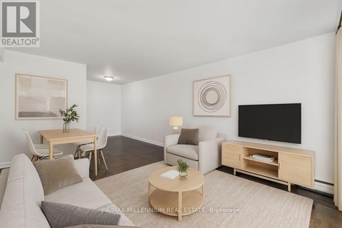 A living room with a couch, a coffee table, a chair, a television, and a painting on the wall.