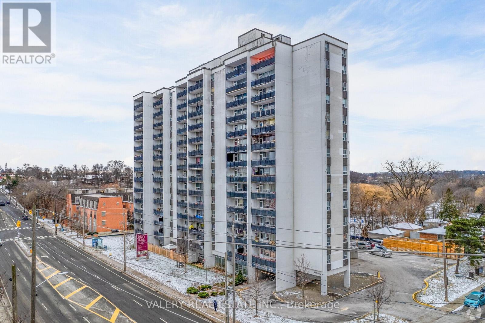 A tall residential building with a flat roof and a balcony on the top floor.