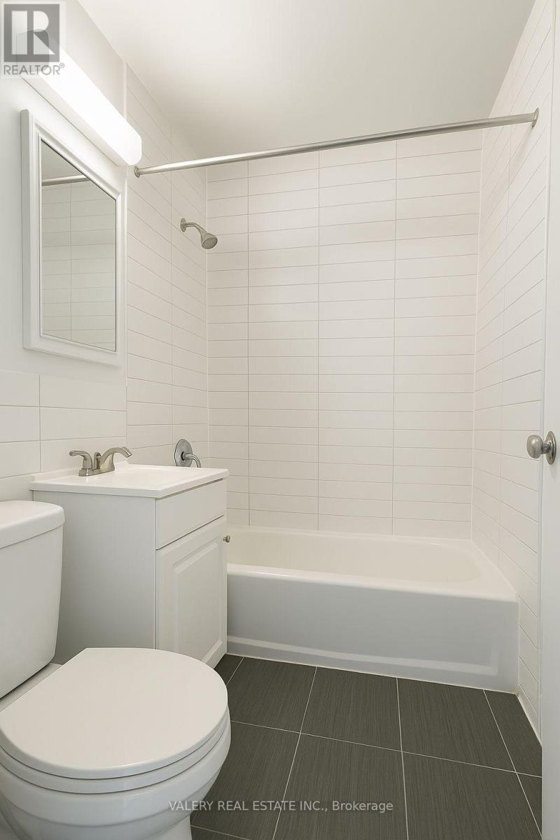 A white toilet sits next to a white sink in a tiled bathroom.