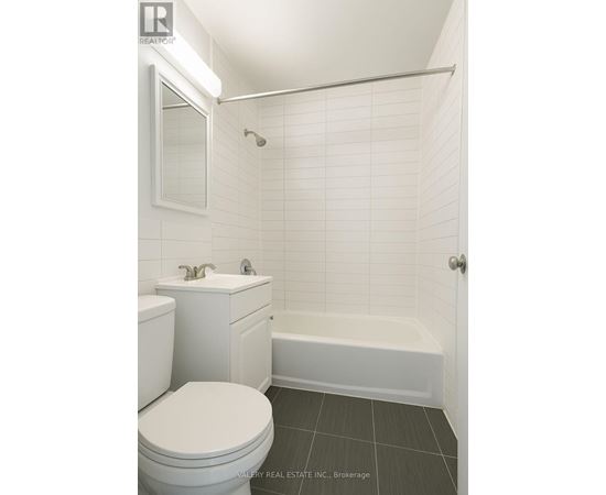 A white toilet sits next to a white sink in a tiled bathroom.