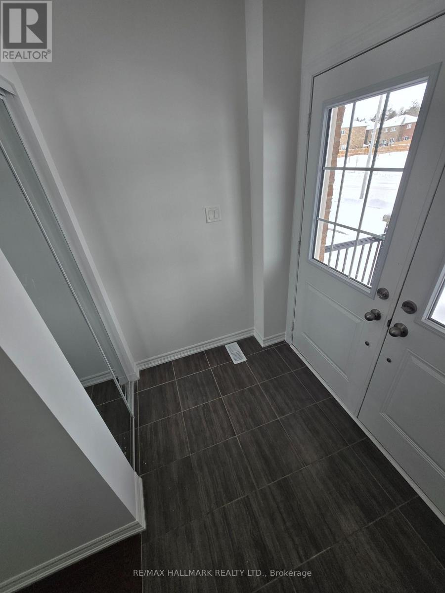 A hallway with a white door and a window with a view of a building outside.