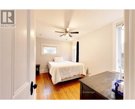 A bedroom with a bed, a ceiling fan, and a window.