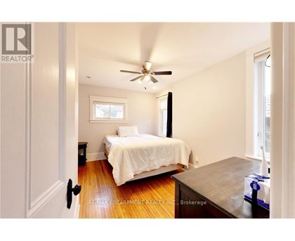 A bedroom with a bed, a ceiling fan, and a window.