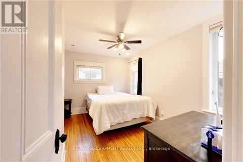 A bedroom with a bed, a ceiling fan, and a window.
