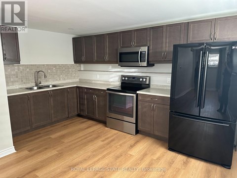 A kitchen with a black fridge and wooden floors.