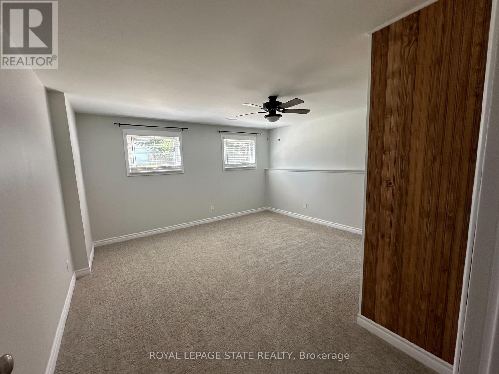 A room with a ceiling fan and two windows.