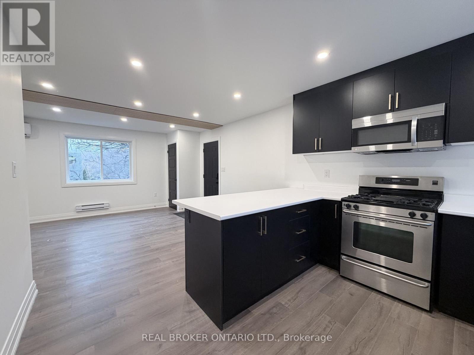 A modern kitchen with black cabinets and stainless steel appliances.