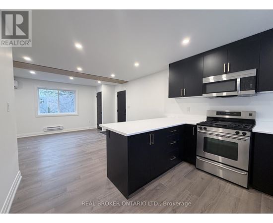 A modern kitchen with black cabinets and stainless steel appliances.