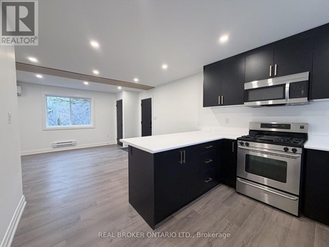 A modern kitchen with black cabinets and stainless steel appliances.