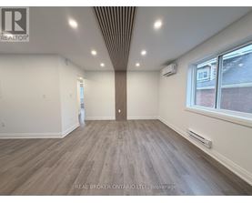 A spacious room with wood flooring and a ceiling with recessed lighting.