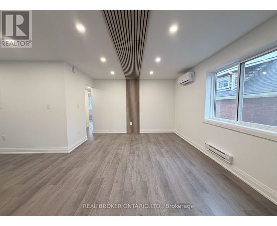 A spacious room with wood flooring and a ceiling with recessed lighting.