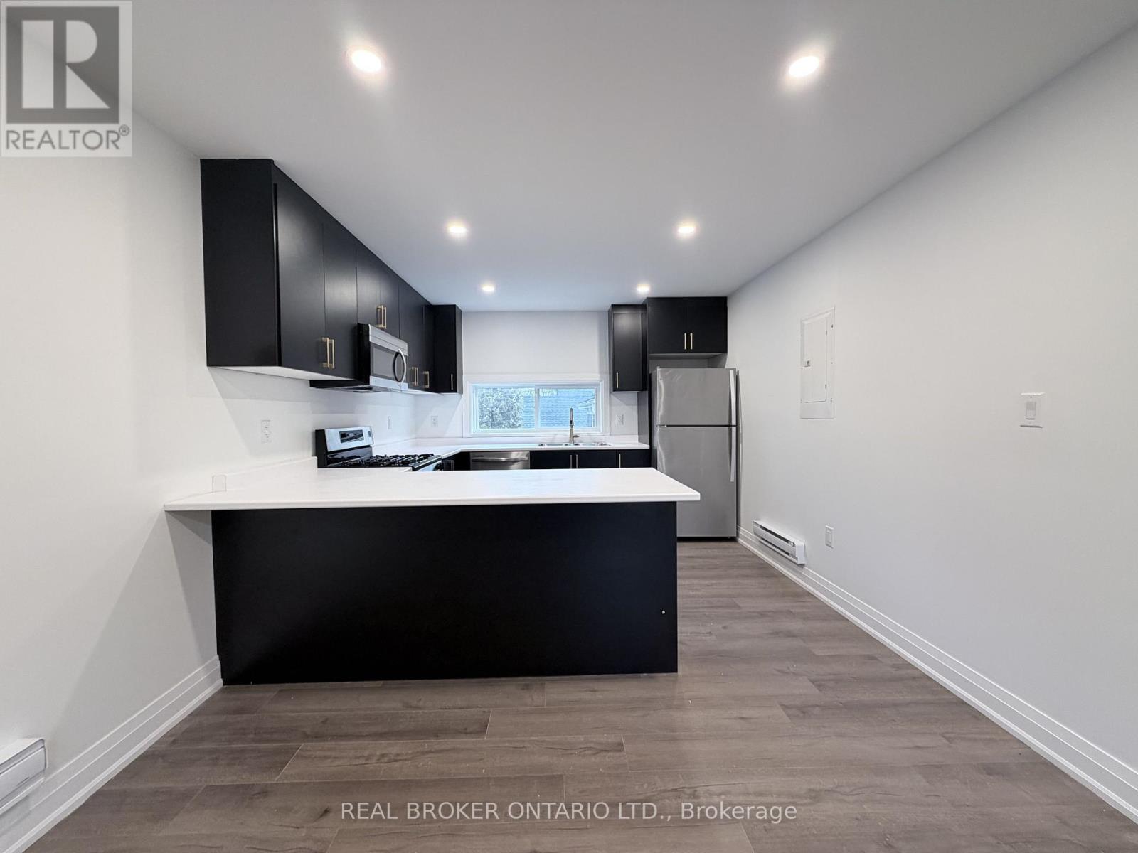 A modern kitchen with black cabinets and a white countertop.