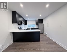 A modern kitchen with black cabinets and a white countertop.