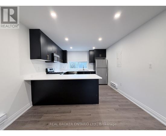 A modern kitchen with black cabinets and a white countertop.