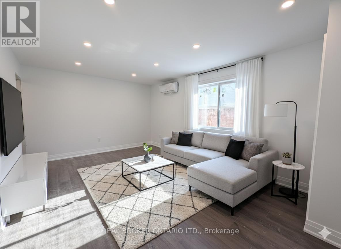 A living room with a white couch, a coffee table, and a television.
