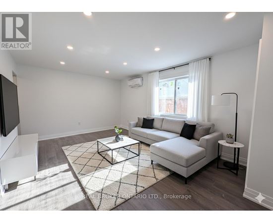 A living room with a white couch, a coffee table, and a television.