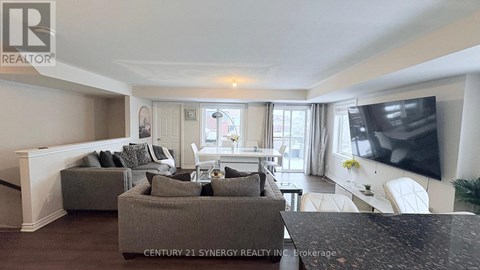 A living room with a grey sofa and a television on the wall.