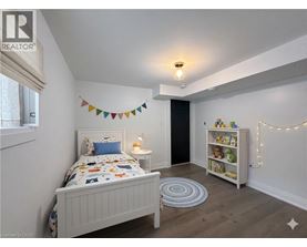 A bedroom with a white bed and a bookshelf with lights strung up.