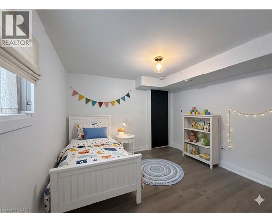 A bedroom with a white bed and a bookshelf with lights strung up.