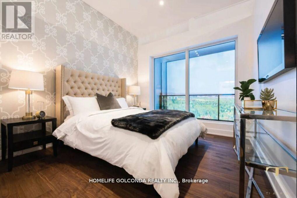 A bedroom with a large bed and a balcony overlooking greenery.