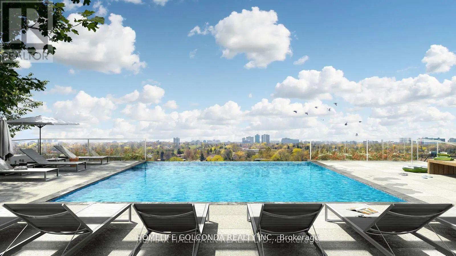 A pool with lounge chairs and a city skyline in the background.