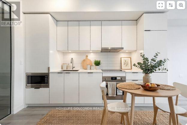 A modern kitchen with white cabinets and a dining table set with a bowl of fruit.