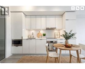 A modern kitchen with white cabinets and a dining table set with a bowl of fruit.