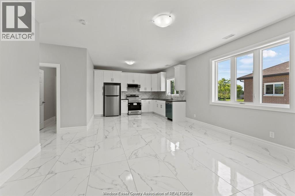 A spacious kitchen with white marble flooring and modern appliances.