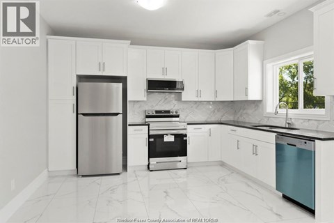 A kitchen with white cabinets and a marble countertop.