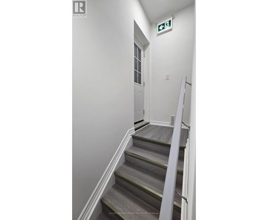 A stairway leading to a door with a green exit sign above it.