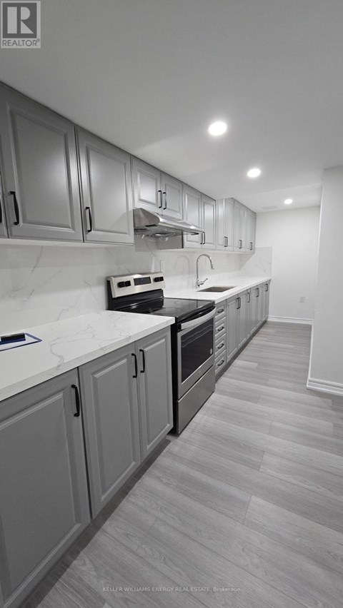 A kitchen with a white counter top and grey cabinets.