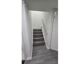 A staircase with a grey carpeted floor and white walls.