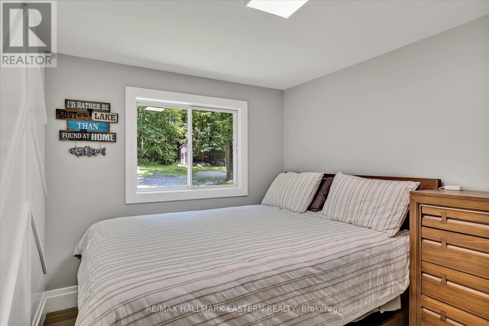 A bedroom with a bed, a window, and a sign on the wall.