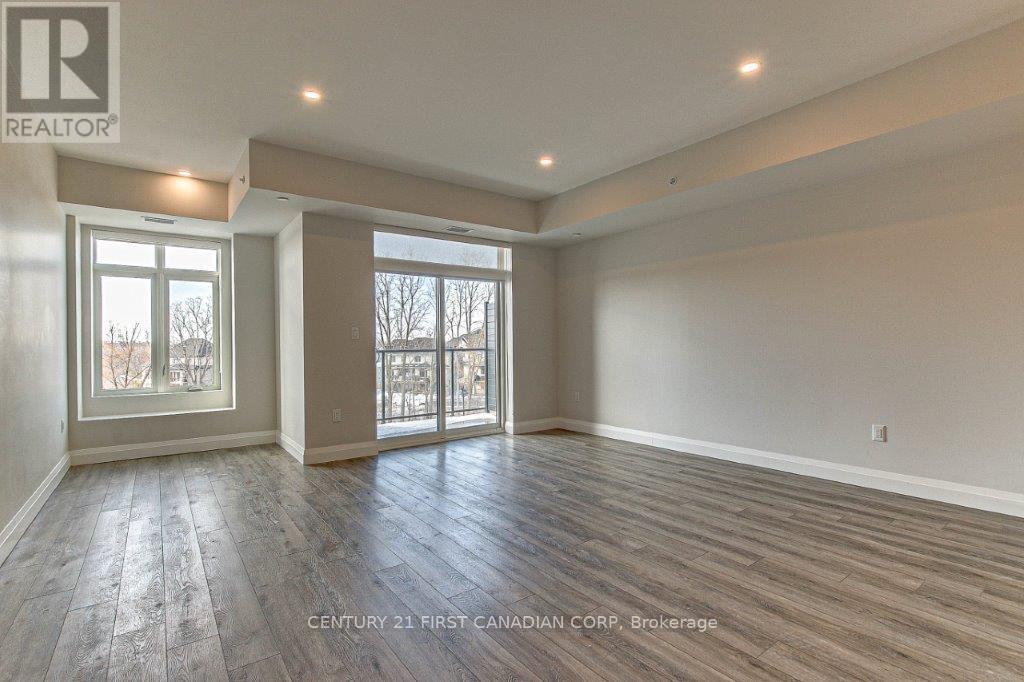A spacious room with wooden flooring and large windows.